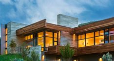 a large modern house with lots of windows on the front and side of it at night