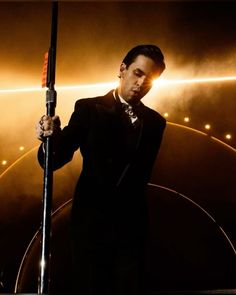 a man in a tuxedo holding onto a pole with lights on the background