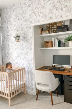 a baby sitting in a crib next to a desk