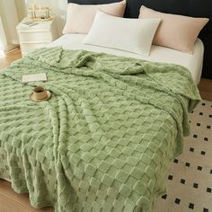 a bed covered in a green blanket and pillows