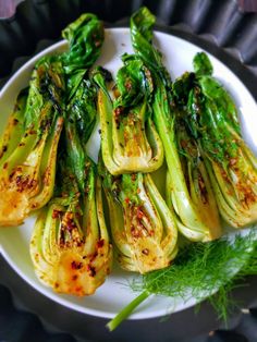 grilled artichokes on a white plate with green garnish