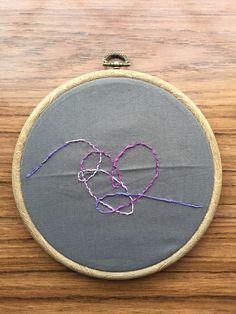 a close up of a embroidery on a piece of cloth with yarn in the shape of a heart