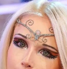 a woman with long blonde hair and black eyeliners on her face is wearing a silver head piece