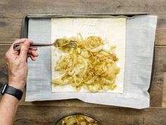 a person cutting onions on top of a sheet of paper with a knife and fork