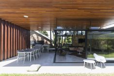 an outdoor patio with tables and chairs under a wooden roof over looking a backyard area