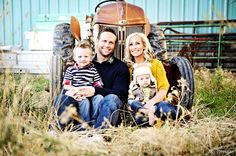 a man, woman and child sitting in front of an old tractor