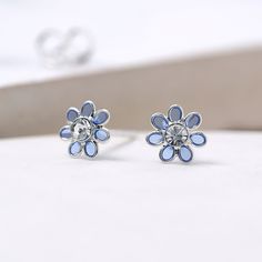 A stunning pair of tiny blue flower stud earrings with a sparkling cubic zirconia in the centre Our lovely little flower earrings are crafted from the finest sterling silver with translucent blue enamel petals and are perfect for bringing a touch of spring to your look. These dainty silver flower earrings feature a classic butterfly and post fastening and are suitable for almost any age. A lovely Christmas gift, stocking filler or for a birthday treat. A wonderfully thoughtful way to mark a mile Blue Sterling Silver Earrings With Flower Charm, Blue Flower-shaped Sterling Silver Earrings, Blue Flower Sterling Silver Earrings, Elegant Blue Birth Flower Earrings, Blue Sterling Silver Flower Earrings, Dainty Blue Flower Earrings, Nickel-free Blue Sterling Silver Flower Earrings, Blue Sterling Silver Flower Earrings Nickel Free, Blue Flower Earrings For Mother's Day