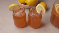 two jars filled with lemonade next to some lemons