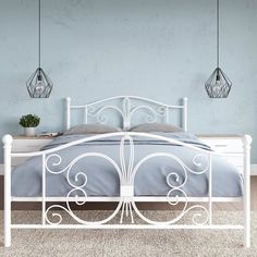 a white metal bed with two lamps hanging from it's headboard and foot board