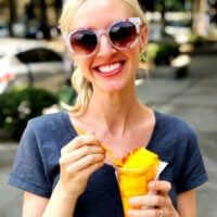 a woman in sunglasses is eating an ice cream cone