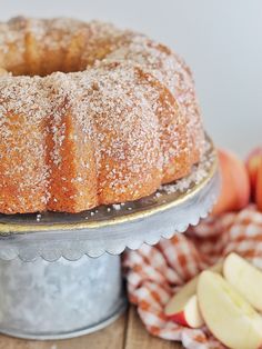 a bundt cake sitting on top of a metal pan next to an apple slice