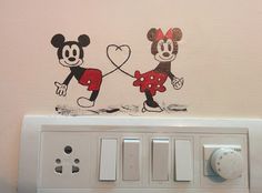 two mickey and minnie mouse wall decals on the side of a light switch box