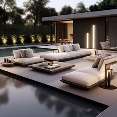 a modern living room with white couches next to a swimming pool at night time