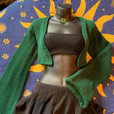 a mannequin wearing a green cardigan and brown skirt on top of a bed