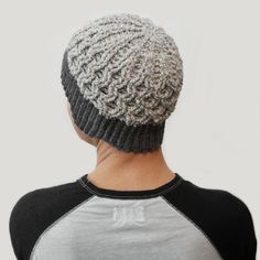 the back of a person wearing a knitted beanie in grey and white colors