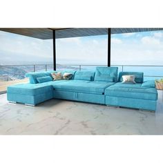 a large blue sectional couch sitting on top of a white floor next to a window