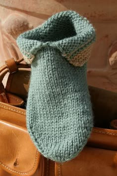 a green knitted mitt sitting on top of a brown bag