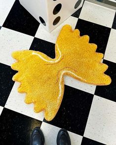 a pair of black shoes standing on a checkered floor next to a yellow rug