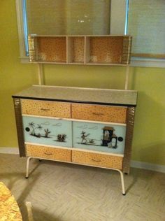 an old dresser with two drawers and some pictures on the front, sitting in a room next to a window