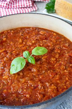 a pot filled with chili and basil on top of a table