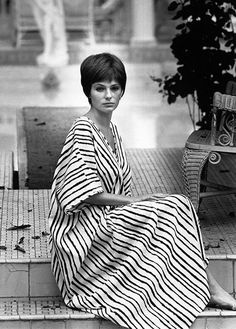 black and white photograph of a woman sitting on steps wearing a striped dress with her legs crossed