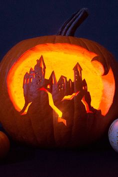 a pumpkin carved to look like a castle on a hill with bats and balls around it