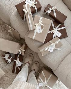 many wrapped presents sitting on the floor next to someone's legs and feet in white socks