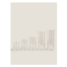 five clear glass vases lined up in a row on a white background with one empty