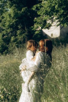 two women in white dresses walking through tall grass