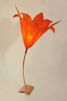 a lamp that is sitting on top of a wooden stand with a flower in it