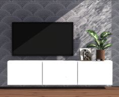 a flat screen tv sitting on top of a white cabinet next to a potted plant