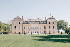 a large building with lots of windows in the middle of a grassy area next to trees