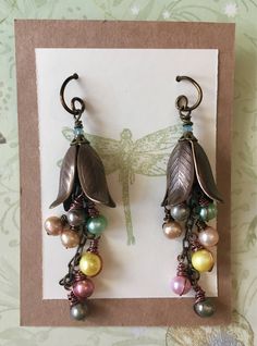 I made these for a friend's wedding, and I loved them so much I decided to put them in the shop. Eight colorful freshwater pearls dangle from a brass chain under solid natural brass petals. The petal bead caps are by Vintaj. Each pearl is hand wrapped with copper wire. The brass flowers are topped with small brass bead caps and tiny mint green crystals. The earring hooks are handmade from 99.9% pure copper wire with a natural brass finish. If you prefer standard brass hooks, please let me know. Pearl Ideas, Brass Flowers, Mint Green Earrings, Polymer Clay Flower Jewelry, Stamped Earrings, Pearl Earrings Wedding, Freshwater Pearl Earrings, Vintage Style Earrings, Jeweled Earrings