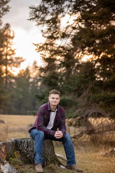 a young man sitting on top of a tree stump