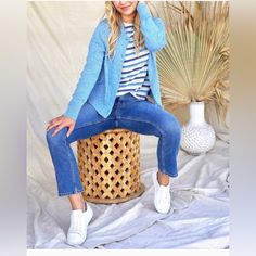 a woman sitting on top of a wicker basket next to a vase and palm tree