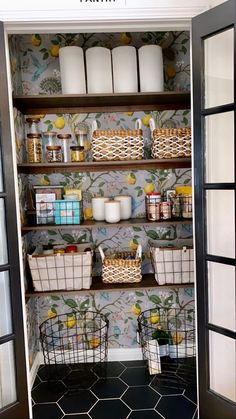 an open pantry door with baskets and containers on the shelves, in front of a wallpapered wall