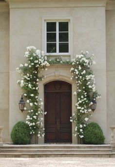 an entrance to a house with white flowers on it