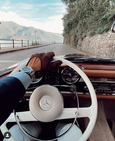 a man driving a car down a road next to the ocean