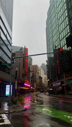 a rainy day in the city with traffic lights and people walking down the street at an intersection