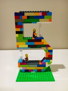 the lego letter e is made out of multi - colored blocks and has a man sitting on it