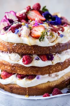 there is a large cake with strawberries and flowers on the top it sits on a plate