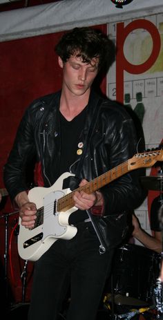 a young man playing an electric guitar on stage