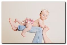 a woman holding a baby in her arms while sitting on top of another person's legs