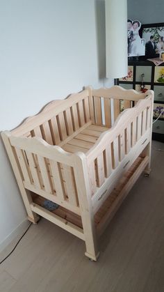 a wooden crib sitting on top of a hard wood floor next to a white wall