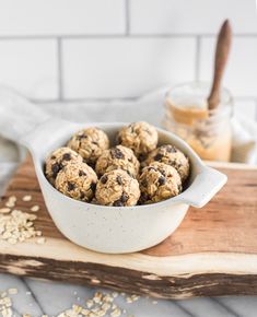 a white bowl filled with oatmeal cookies on top of a wooden cutting board