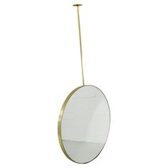 a round mirror hanging from a brass rod