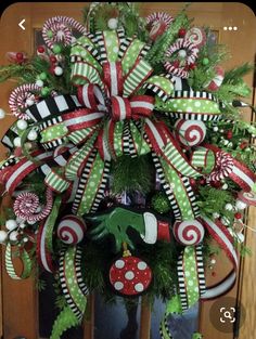 a christmas wreath with candy canes and green, red and white decorations on the front door