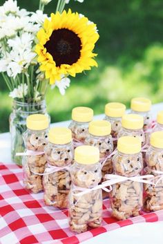 there are many jars with cookies in them on the table next to a sunflower