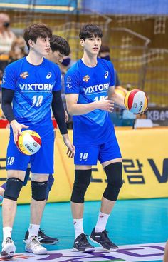 three men standing next to each other on a court with volleyball balls in their hands