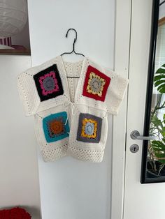 four crocheted squares hanging from a hook on a door hanger in front of a white door